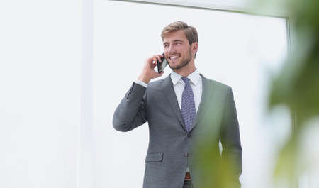 businessman talking on a mobile phone standing near the office window