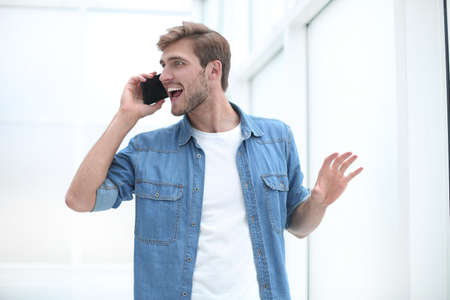 young man talking on the phone standing in officeの写真素材