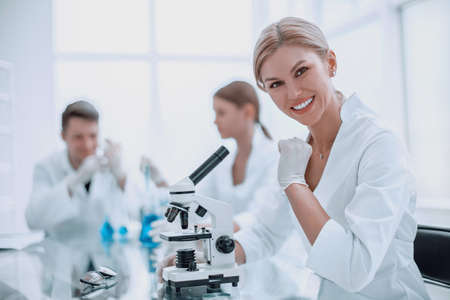 successful female scientist sitting in front of a microscopeの写真素材