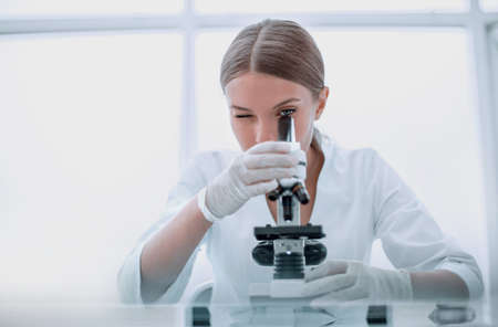 female scientist with a microscope works in the laboratoryの写真素材
