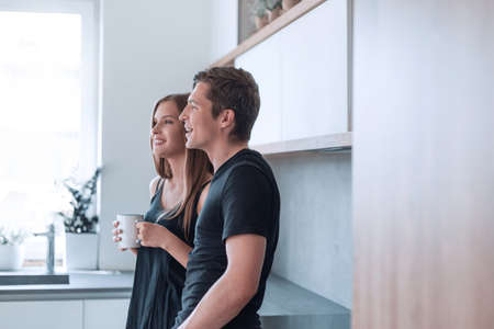 happy young couple standing in the kitchen in their house.の写真素材