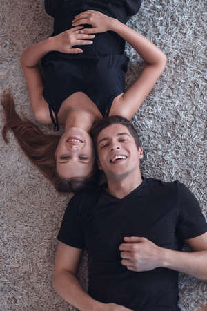 happy young couple lying on the carpet and looking at the cameraの写真素材