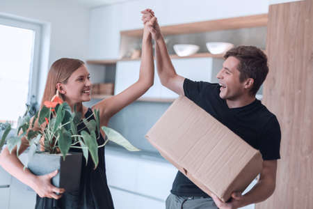 young couple gives each other a high five standing in their new apartment