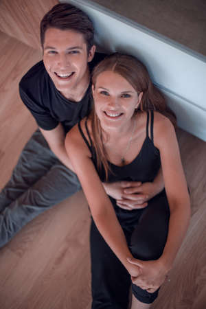 happy young couple sitting on the floor and looking at the cameraの写真素材