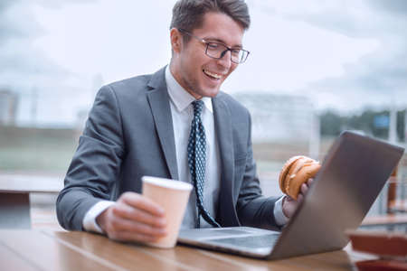 smiling businessman sitting at a table in a street cafeの写真素材