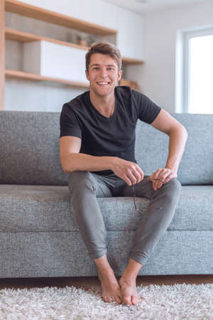 successful young man sitting on sofa in living roomの写真素材