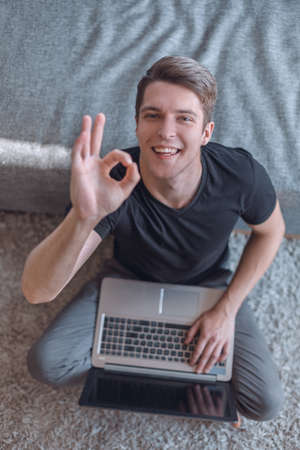 happy young man with laptop showing gesture OKの写真素材