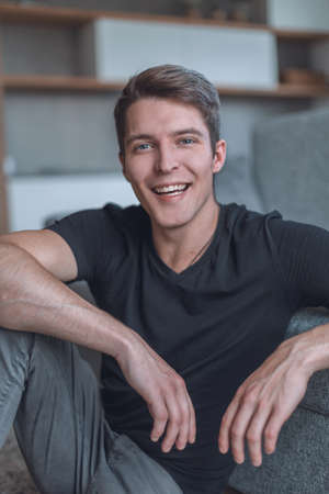 happy guy sitting on the floor and looking at the camera