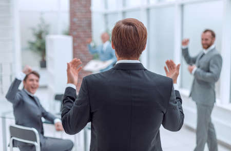 rear view. happy businessman telling something to his business team.の写真素材