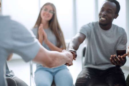 close up. smiling guy shaking hands with his friendの写真素材