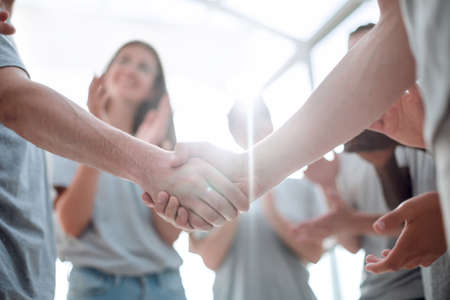 handshake of young people on the background of the applauding teamの写真素材
