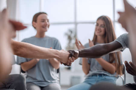 close up. smiling guy shaking hands with his friendの写真素材