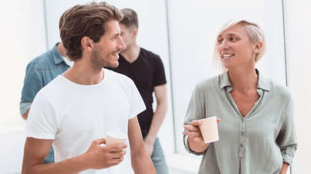 employees with coffee glasses passing through the corridor of the office
