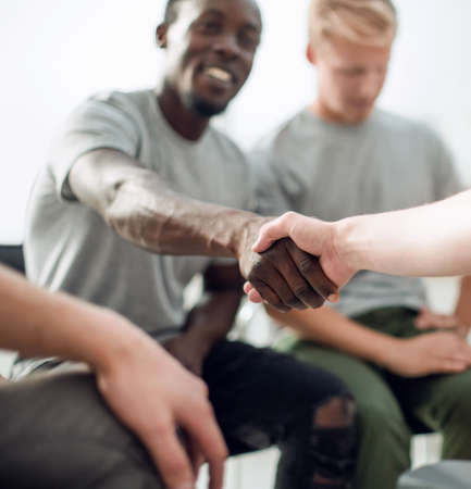 close up. smiling guy shaking hands with his friendの写真素材