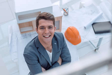 male architect sitting at his Desk and pointing to a copy of the spaceの写真素材