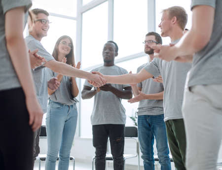 young people shaking hands, standing in a circle of friends.の写真素材