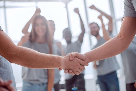 handshake of young people on the background of the jubilant teamの写真素材