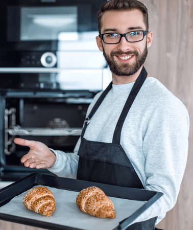 smiling man holding a tray of fresh croissantsの写真素材