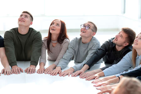 group of young people sitting at a table and looking up