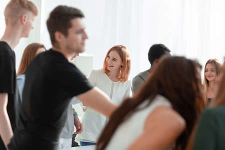 group of diverse young people standing around a round tableの写真素材