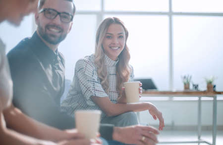 employees of the company with coffee glasses sitting in the office lobby