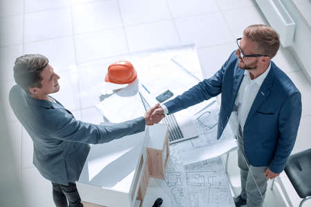 business people shaking hands in the architectural office.の写真素材