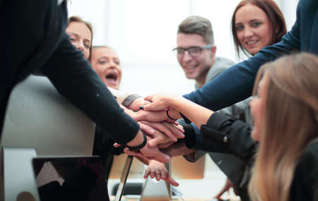 group of employees forming a stack of hands on the desktop