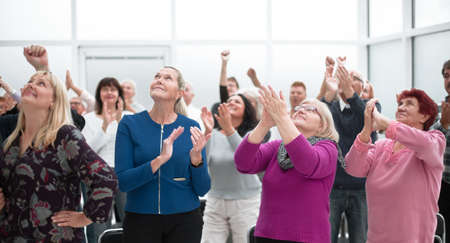Audience applaud with raised hands in the meeting
