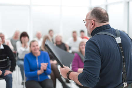 Mature caucasian man gives a speech in meeting in modern open officeの写真素材