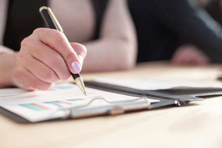 Hand of businesswoman writing on paper in officeの写真素材