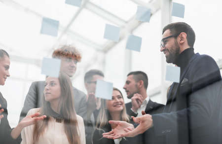 Manager pointing to a glass Board with sticky notesの写真素材