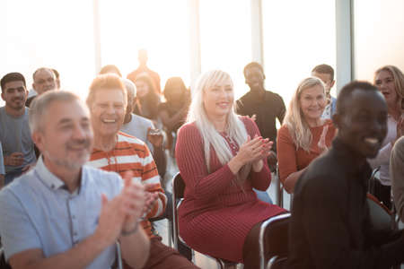 Smiling audience applauding at a business seminarの写真素材