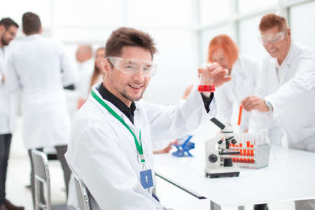 young scientist looking at a test tube with test results.