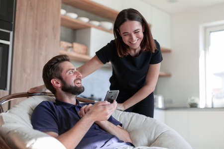 Woman and man using smartphone at kitchen