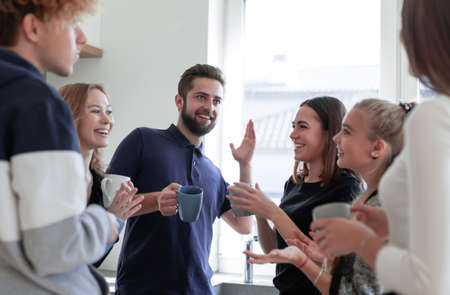 Group of happy men and women in conversation while drinking teaの写真素材