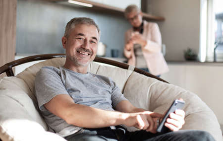 casual man with a smartphone sitting in a comfortable chair.の写真素材