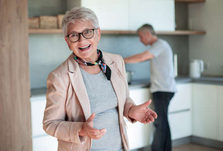 smiling old lady standing in the kitchen .の写真素材