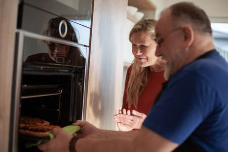 adult couple prepares homemade cakes in a new oven.の写真素材