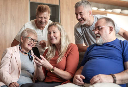 Mature woman showing friends photos on her smartphone.