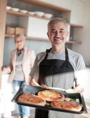 smiling man with homemade cakes standing in his kitchen .の写真素材
