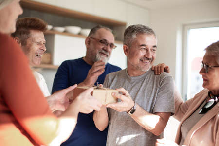 friends congratulating an elderly couple on their housewarming.