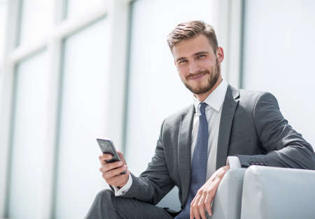 businessman sitting in an armchair with phoneの写真素材