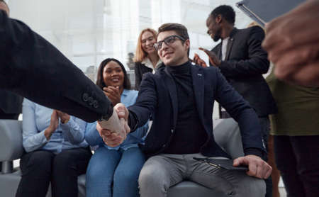 employees congratulating their colleague at a work meeting.