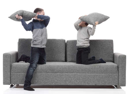 two brothers have a pillow fight on the couch.の写真素材