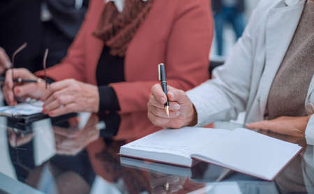 Business woman sitting at her workplace and making notes