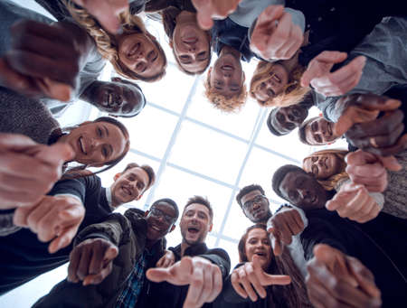 group of diverse young people standing in a circle and pointing at youの写真素材