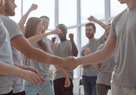 handshake of young people on the background of the jubilant team