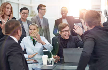 Cheerful creative business team sitting around table at office