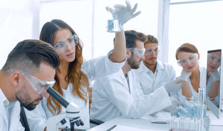 Scientists examining attentively pipette with blue fluid in labo