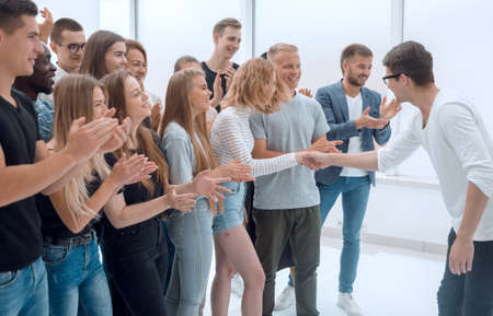young people shaking hands, standing among their friends